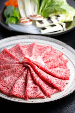 Lezzetli wagyu sığır eti dilimleri ve taze sebzelerin yakın görüntüsü.        