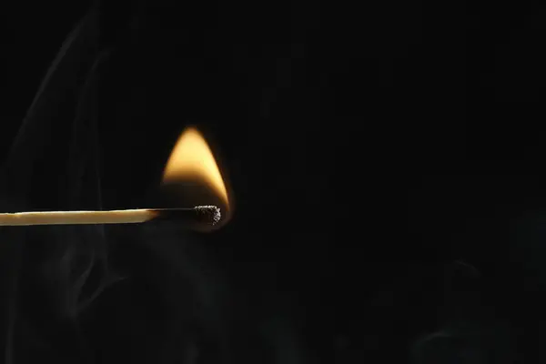 burning match with fire flame on black background