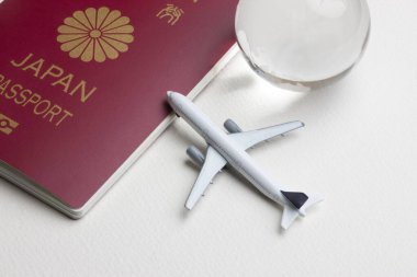 Japon pasaportu, oyuncak uçak ve beyaz arka planda kristal küre. 