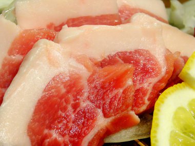 Dilimlenmiş biftek, arka planda taze yemek, yakın plan.