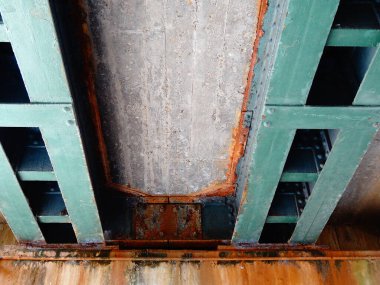 Yakın plan beton tavan yapısını destekleyen yıpranmış metal kirişleri gösteriyor