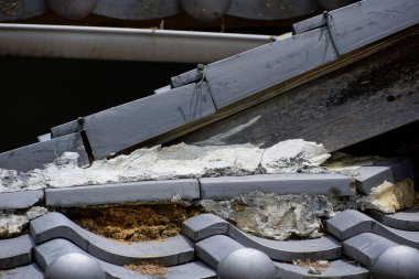 Hasarlı çatı kiremitleri açık yalıtım ve kırık yapıyı gösteriyor