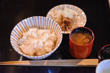 Buharda pişen beyaz pirinç miso kasesinin yanında.