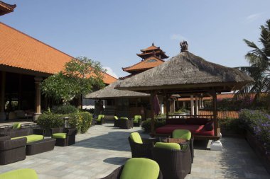 Yeşil sandalyelerin ve geleneksel mimarinin yer aldığı açık hava oturma alanı