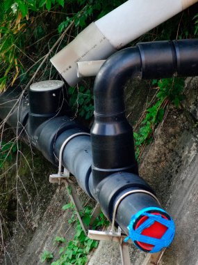 Beton duvar boyunca uzanan siyah plastik borular.