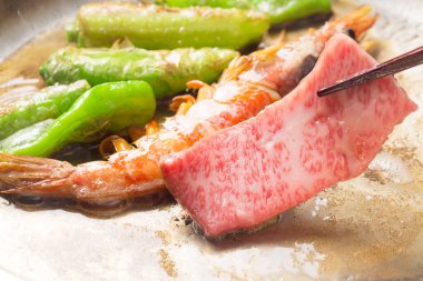 Grilled beef and vegetables prepared on a hot plate at a traditional Japanese restaurant during lunchtime clipart