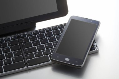 Beyaz arkaplanda bilgisayar klavyesinin ve cep telefonunun yakın görüntüsü                 