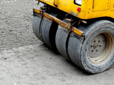 İnşaat sırasında çakıl sıkıştıran sarı yol silindiri