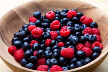 Taze yaban mersini ve ahududu. Tahta kasede organik meyveler