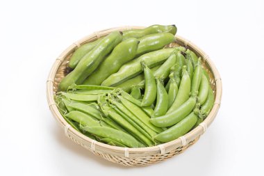 Yeşil fasulye ve bezelyeler beyaz arka planda bambu sepetinde.