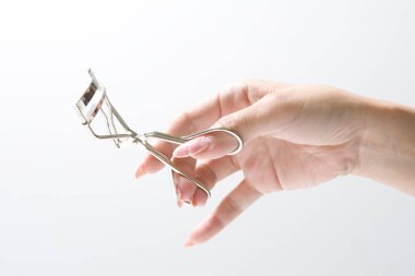 Beyaz arka planda metal kirpik bigudisi tutan kadın