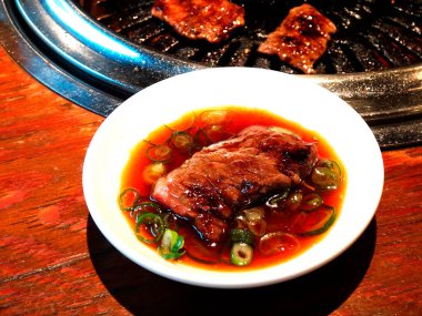 Soslu ızgara et ve yeşil soğan.