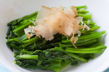 Üstünde bonito taneleri olan buğulanmış yeşiller.