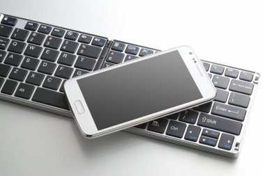 Beyaz arkaplanda bilgisayar klavyesinin ve cep telefonunun yakın görüntüsü                 
