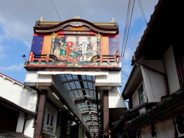 Dar alışveriş sokağının üstündeki renkli geleneksel Japon kapısı