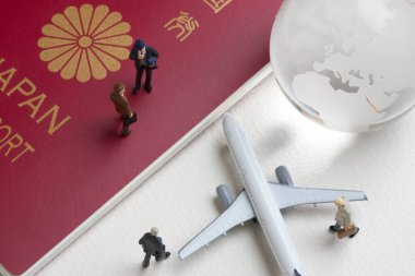 Oyuncak uçak, cam dünya küresi ve Japon pasaportlu minyatür insanlar.