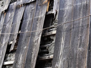 Eski taş duvar yapısını kaplayan eskimiş ahşap tahtalar.