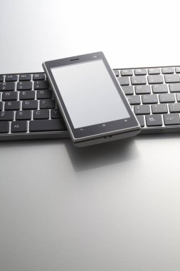 Beyaz arkaplanda bilgisayar klavyesinin ve cep telefonunun yakın görüntüsü                 