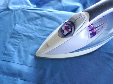 Modern elektrikli demir masa yüzeyine mavi kumaş bastırıyor