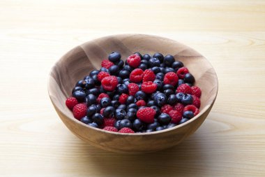 Taze yaban mersini ve ahududu. Tahta kasede organik meyveler