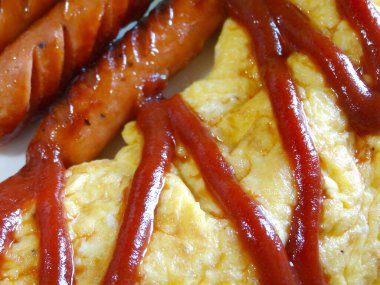 Kızarmış sosis ve omlet ile lezzetli yemek manzarası.    