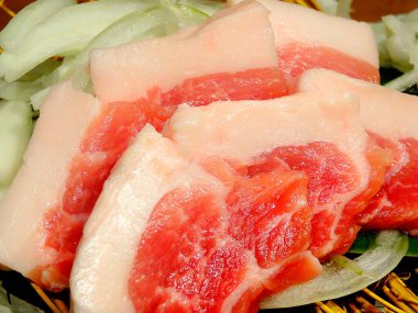 Dilimlenmiş biftek, arka planda taze yemek, yakın plan.