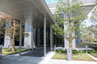 Metalik tepe örtüsü, Sütunları ve Yeşilliği olan Modern Bina Girişi