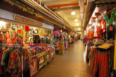 Tekstil ve giysi tezgahlarıyla kaplı bir pazar koridorunun iç görünümü