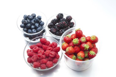 Beyaz arka planda çeşitli taze böğürtlenler. Çilek, ahududu, yabanmersini ve böğürtlen