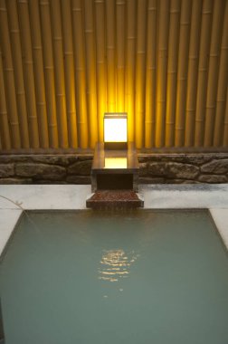 Sakin bir açık hava su özelliğinin üzerinde yanan bir fener.