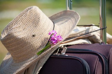 Bavulunda pembe çiçek olan hasır şapka, seyahat konsepti. 