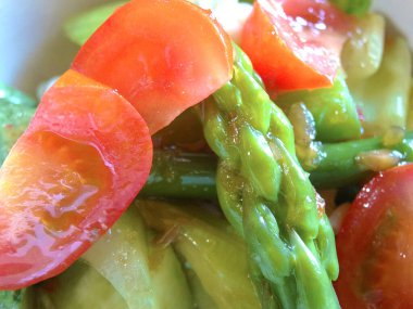 Domatesli ve kuşkonmaz soslu taze sebze salatasının yakın plan görüntüsü.      