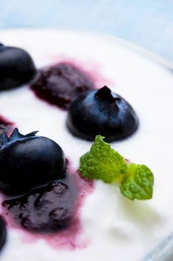 Yoğurtlu yaban mersini ve bardakta nane yaprağı.