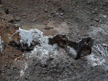 Gri kül ve dağınık kayalarla çevrili yanmış molozlar.