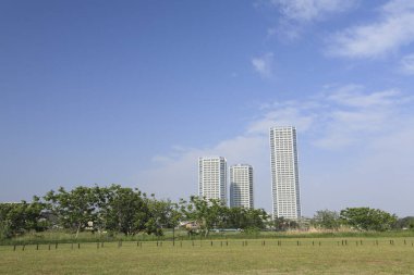 modern şehir binaları, yeşil ağaçlar ve mavi gökyüzü