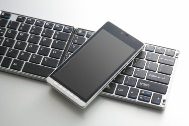 Beyaz arkaplanda bilgisayar klavyesinin ve cep telefonunun yakın görüntüsü                 