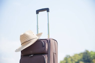 Açık havada duran hasır şapkalı bavul, seyahat kavramı. 