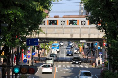 Şehir demiryolunun iyi bakımlı dış hatları yoğun bir Japon caddesine paraleldir..