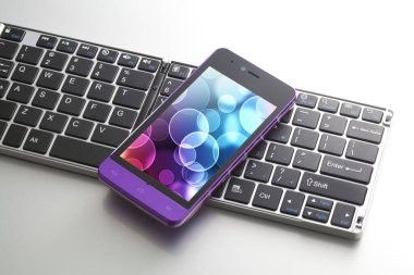 Beyaz arkaplanda bilgisayar klavyesinin ve cep telefonunun yakın görüntüsü                 