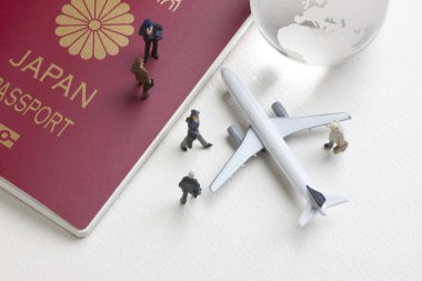 Oyuncak uçak, cam dünya küresi ve Japon pasaportlu minyatür insanlar.