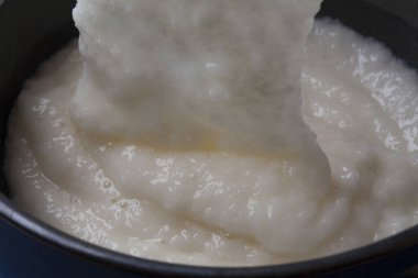 Kalın yulaf lapası tencerede karıştırılıyor.