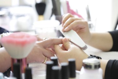 Kadın manikürle oje yaptırıyor..