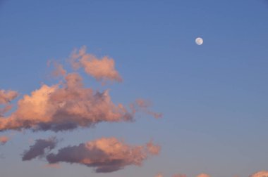 Mavi gökyüzünde ay kabarık bulutlarla 