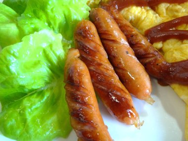 Kızarmış sosis ve omlet ile lezzetli yemek manzarası.    