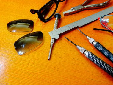 Ahşap yüzeydeki hassas aletler kullanılarak gözlük tamir ediliyor