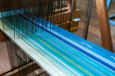 Geleneksel dokuma tezgahından geçen renkli iplikleri gösteren yakın plan