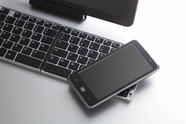 Beyaz arkaplanda bilgisayar klavyesinin ve cep telefonunun yakın görüntüsü                 