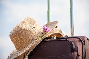 Bavulunda pembe çiçek olan hasır şapka, seyahat konsepti. 