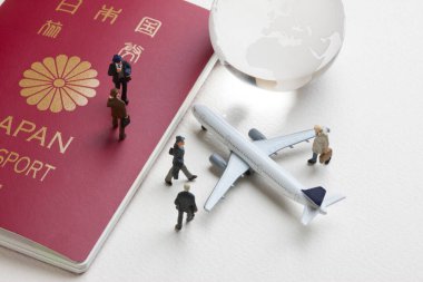 Oyuncak uçağı, cam dünya küresi ve Japon pasaportu olan minyatür insanlar. seyahat kavramı
