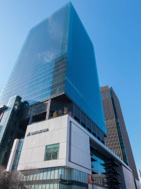 Modern cam gökdelen, mavi gökyüzünü yansıtıyor. Şehir caddesinin üzerinde yükseliyor.